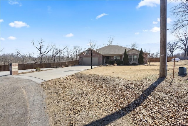 view of front facade featuring concrete driveway, an attached garage, and fence