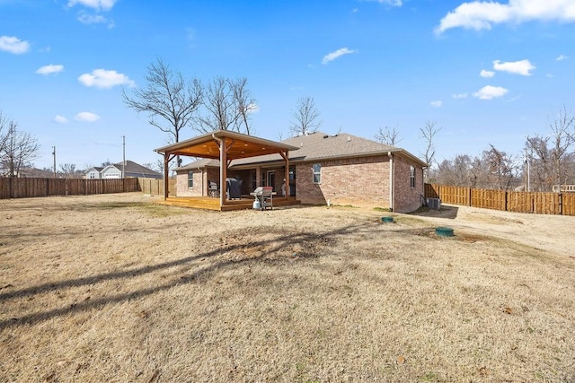 back of house featuring brick siding, a wooden deck, and a fenced backyard