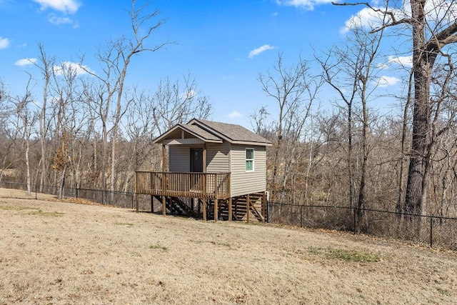 exterior space with a wooded view, a front lawn, a wooden deck, stairs, and a fenced backyard