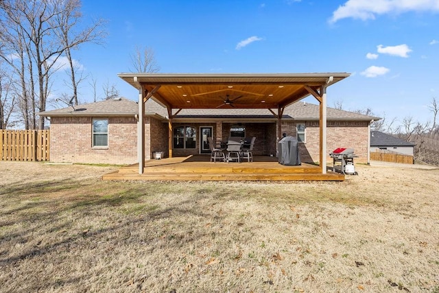 back of property with brick siding, fence, a wooden deck, roof with shingles, and a ceiling fan