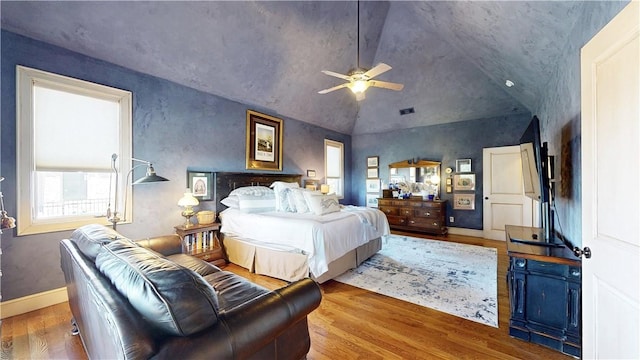 bedroom with visible vents, a ceiling fan, wood finished floors, baseboards, and vaulted ceiling