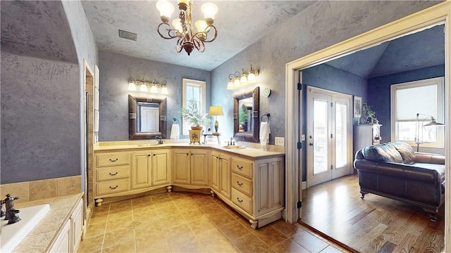 full bath featuring a bathtub, visible vents, vanity, and an inviting chandelier