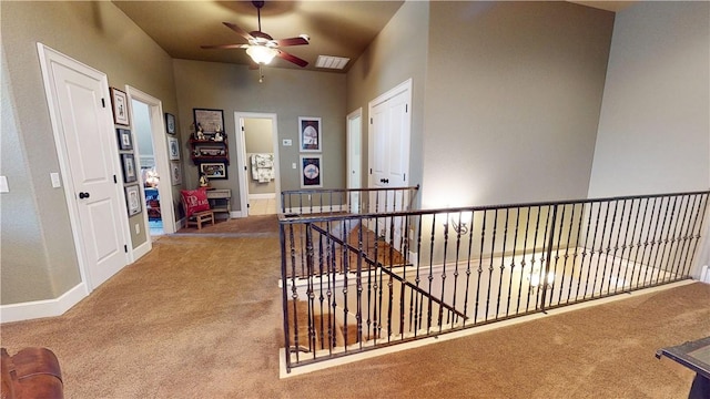 hall featuring visible vents, an upstairs landing, carpet, and baseboards