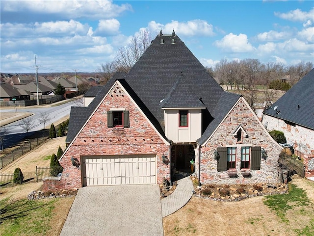 view of front of property featuring a shingled roof, fence, a front yard, stone siding, and driveway