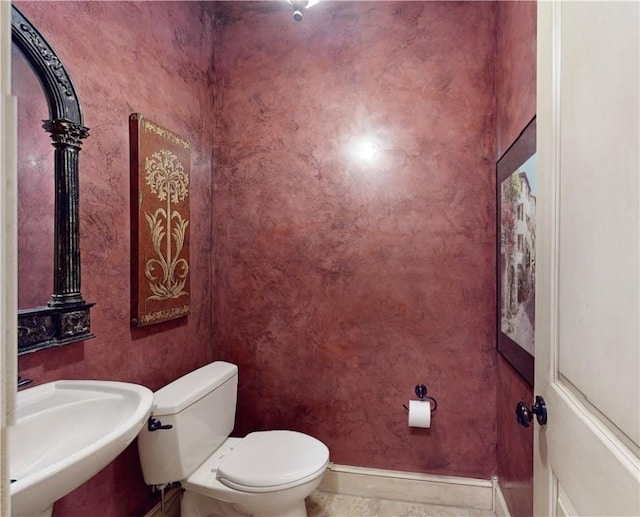 bathroom featuring toilet, baseboards, and a sink