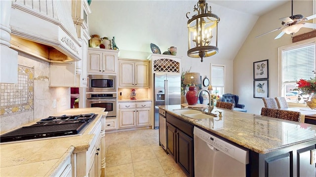 kitchen featuring lofted ceiling, custom exhaust hood, a sink, built in appliances, and ceiling fan with notable chandelier