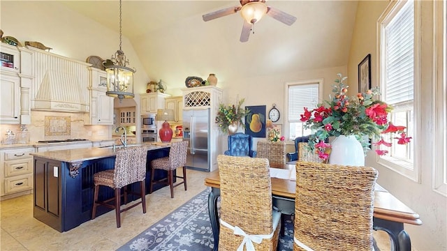 dining room with high vaulted ceiling and ceiling fan with notable chandelier