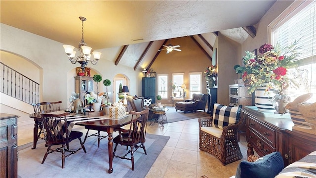 dining space with beamed ceiling, high vaulted ceiling, ceiling fan with notable chandelier, arched walkways, and light tile patterned flooring