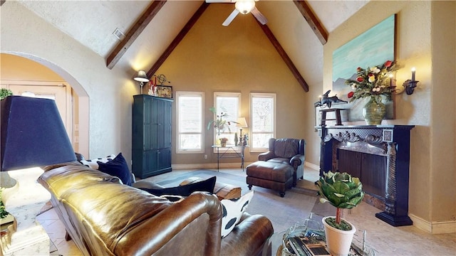 living area featuring beam ceiling, high vaulted ceiling, a ceiling fan, a high end fireplace, and arched walkways