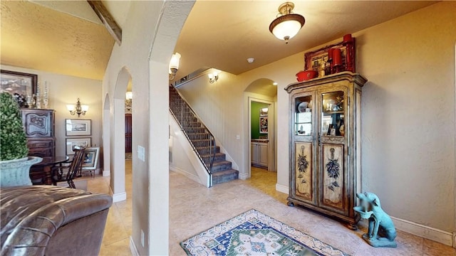 interior space with tile patterned floors, baseboards, and arched walkways