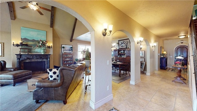 living area with arched walkways, a fireplace, baseboards, and ceiling fan