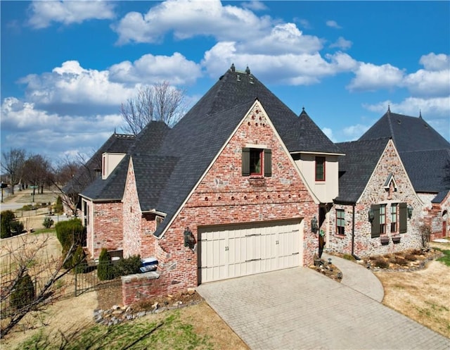 view of front of home featuring decorative driveway, fence, an attached garage, a shingled roof, and brick siding