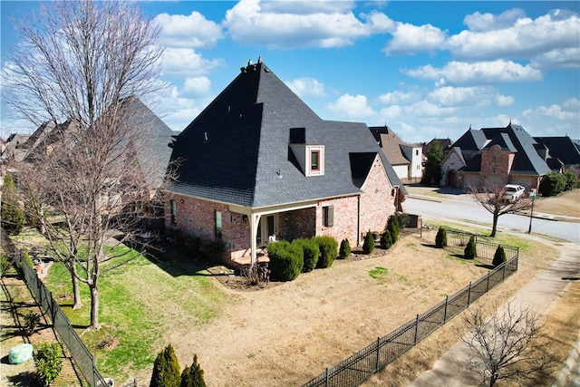 view of side of property with a yard, fence, brick siding, and a shingled roof