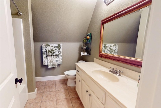 bathroom with vanity, baseboards, vaulted ceiling, tile patterned floors, and toilet