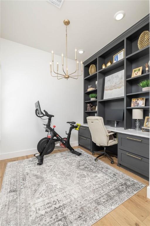 office space featuring baseboards, light wood finished floors, and a chandelier