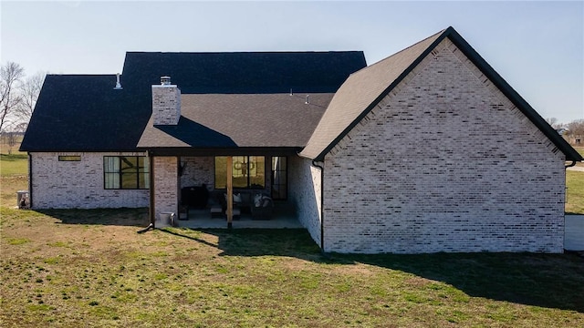 rear view of house featuring a patio area, a lawn, brick siding, and a chimney