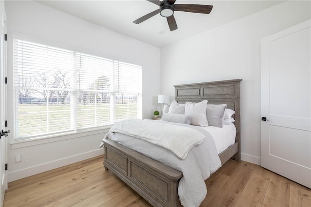 bedroom with ceiling fan, baseboards, and light wood-style flooring