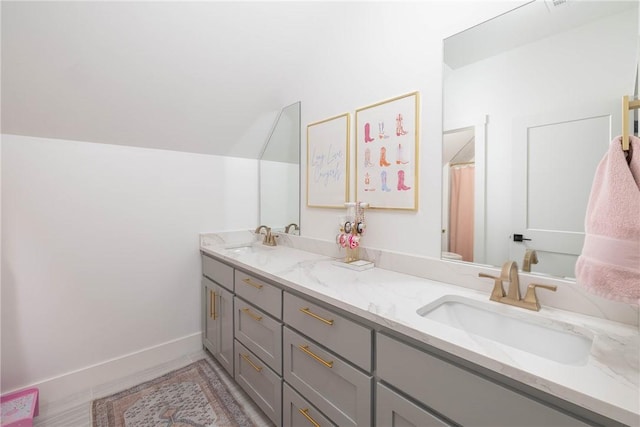 full bath featuring a sink, baseboards, and double vanity