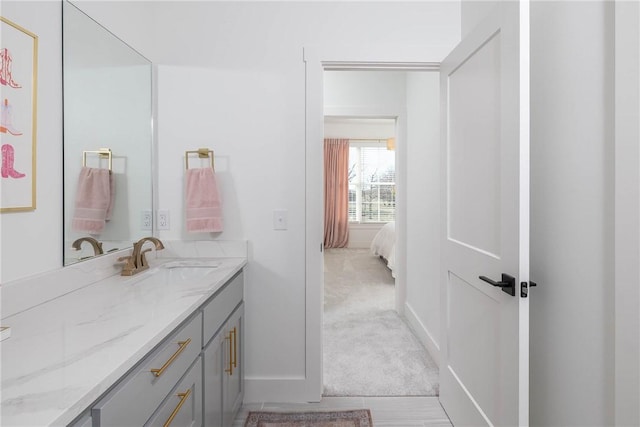 ensuite bathroom featuring ensuite bath, vanity, and baseboards