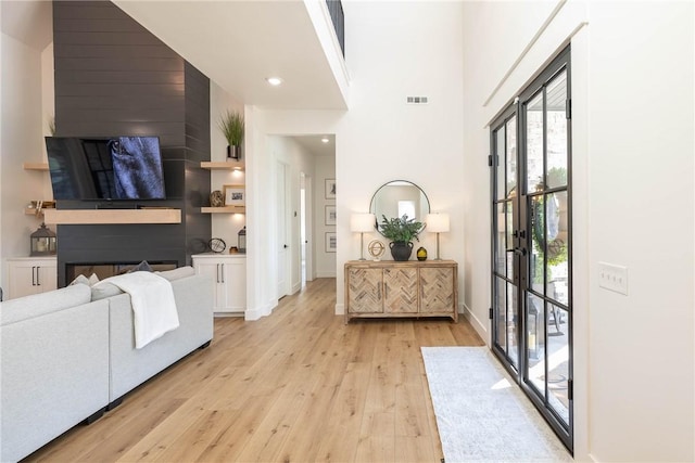 entrance foyer featuring visible vents, baseboards, recessed lighting, light wood-style floors, and a towering ceiling