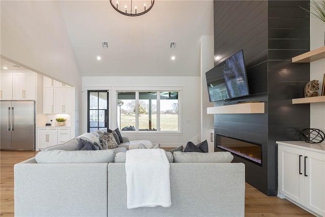 living room with recessed lighting, light wood-type flooring, visible vents, and a glass covered fireplace