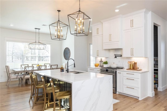 kitchen featuring a sink, tasteful backsplash, a notable chandelier, and stainless steel range