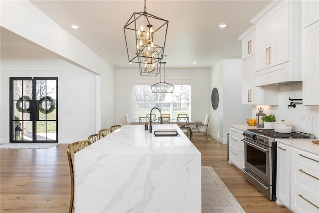 kitchen featuring a sink, a notable chandelier, high end stove, and a wealth of natural light