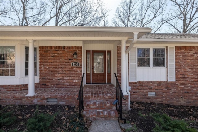 view of exterior entry with crawl space and brick siding