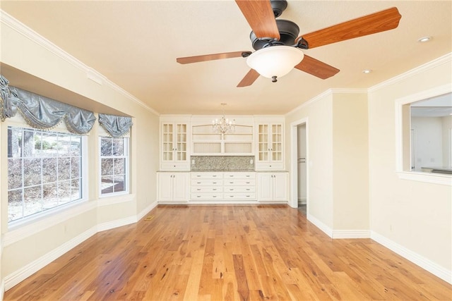 unfurnished living room with ceiling fan with notable chandelier, baseboards, crown molding, and light wood-style floors