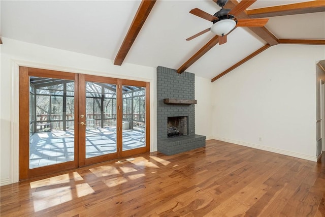 unfurnished living room featuring wood finished floors, a fireplace, baseboards, ceiling fan, and vaulted ceiling with beams