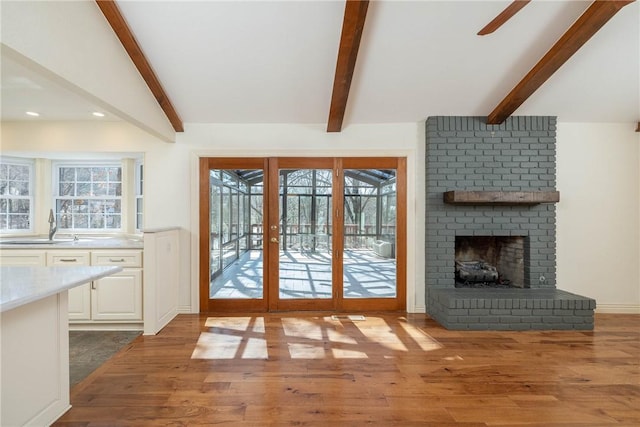 doorway to outside with a sink, wood finished floors, ceiling fan, and vaulted ceiling with beams