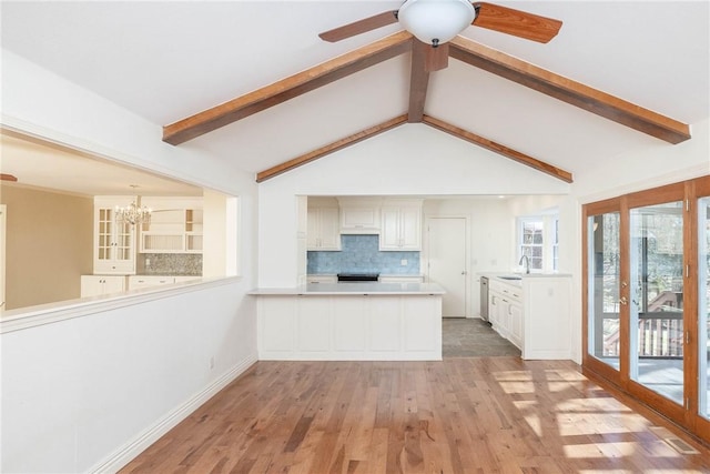 kitchen featuring lofted ceiling with beams, a sink, tasteful backsplash, ceiling fan with notable chandelier, and light wood-type flooring