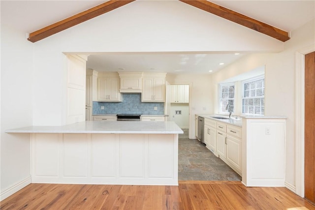 kitchen featuring a peninsula, a sink, stainless steel appliances, light countertops, and backsplash