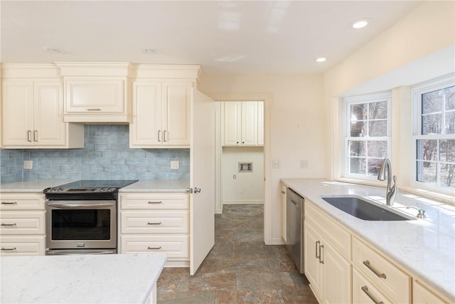 kitchen featuring stone finish flooring, backsplash, appliances with stainless steel finishes, and a sink