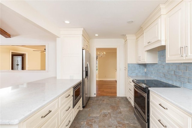 kitchen featuring baseboards, an inviting chandelier, stainless steel appliances, stone finish floor, and backsplash