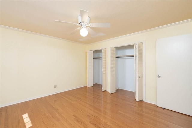 unfurnished bedroom featuring two closets, ornamental molding, a ceiling fan, light wood finished floors, and baseboards