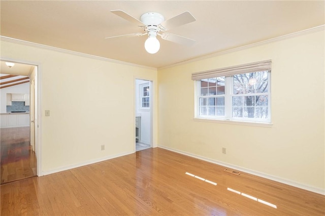 unfurnished room featuring visible vents, ornamental molding, a ceiling fan, wood finished floors, and baseboards