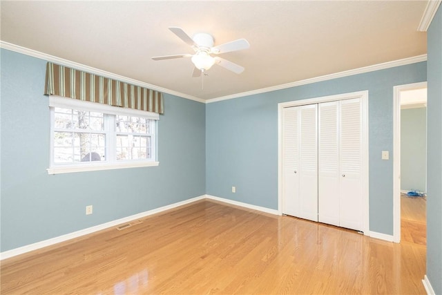 unfurnished bedroom with crown molding, wood finished floors, a closet, and baseboards