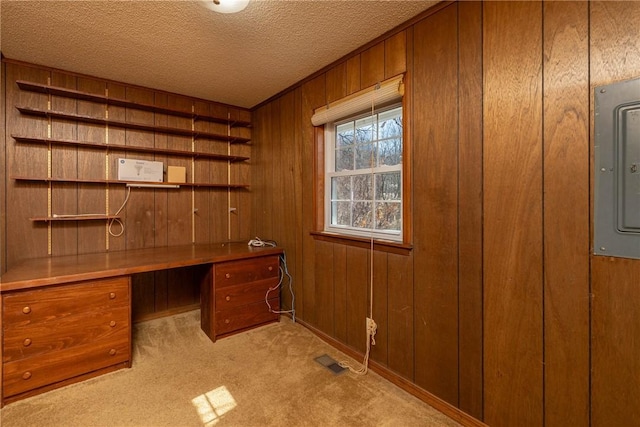 home office featuring visible vents, wooden walls, carpet floors, electric panel, and a textured ceiling