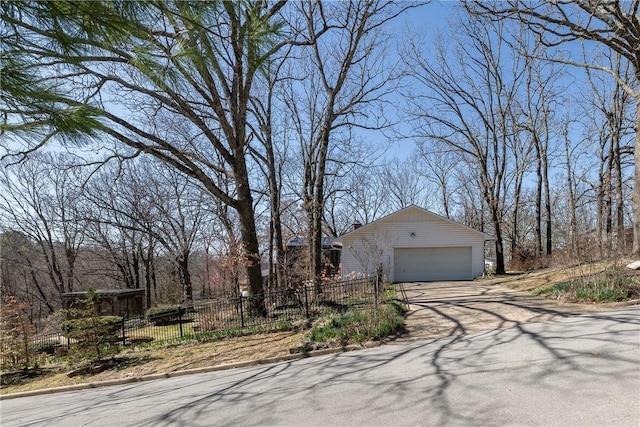 exterior space with concrete driveway, fence, and an outbuilding