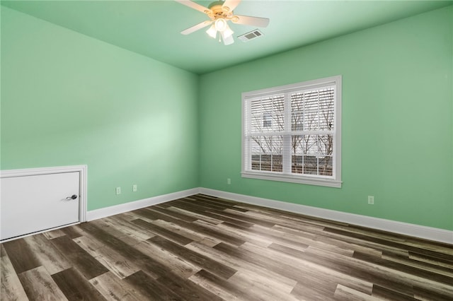 spare room with ceiling fan, visible vents, baseboards, and wood finished floors