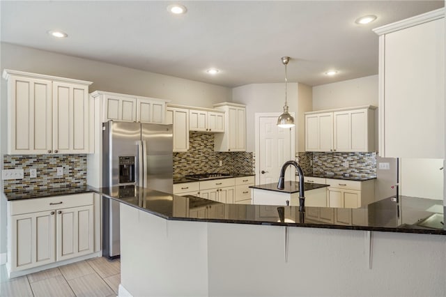 kitchen featuring decorative light fixtures, stainless steel fridge, backsplash, and a peninsula