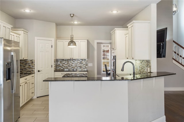 kitchen featuring tasteful backsplash, appliances with stainless steel finishes, a peninsula, and hanging light fixtures