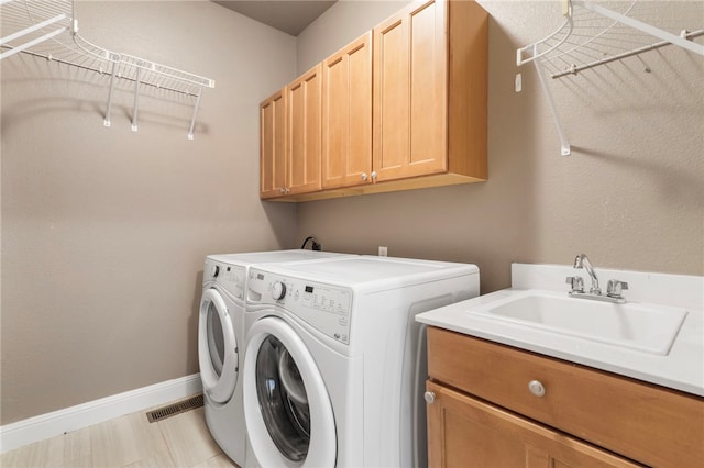 laundry area with visible vents, a sink, baseboards, cabinet space, and separate washer and dryer