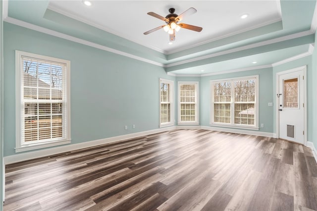 spare room with a tray ceiling, baseboards, wood finished floors, and a ceiling fan