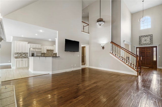 unfurnished living room featuring recessed lighting, baseboards, stairs, and light wood finished floors