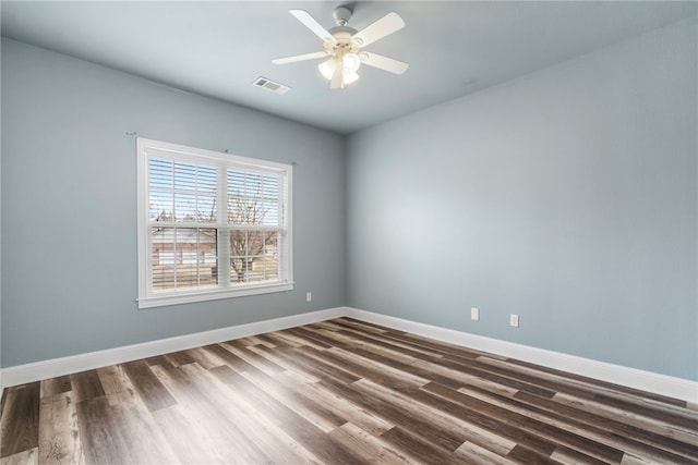 spare room with visible vents, ceiling fan, dark wood-type flooring, and baseboards