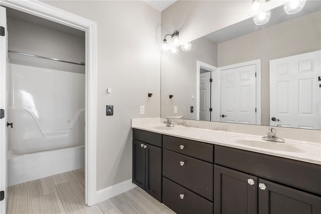 bathroom featuring a sink, shower / bathing tub combination, baseboards, and double vanity