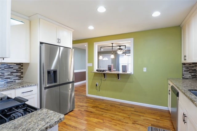 kitchen with light wood finished floors, tasteful backsplash, ceiling fan, stainless steel appliances, and white cabinetry