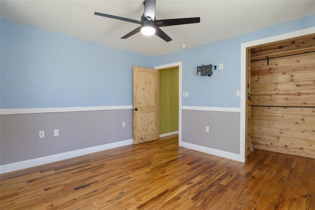 unfurnished bedroom with ceiling fan, baseboards, and wood finished floors